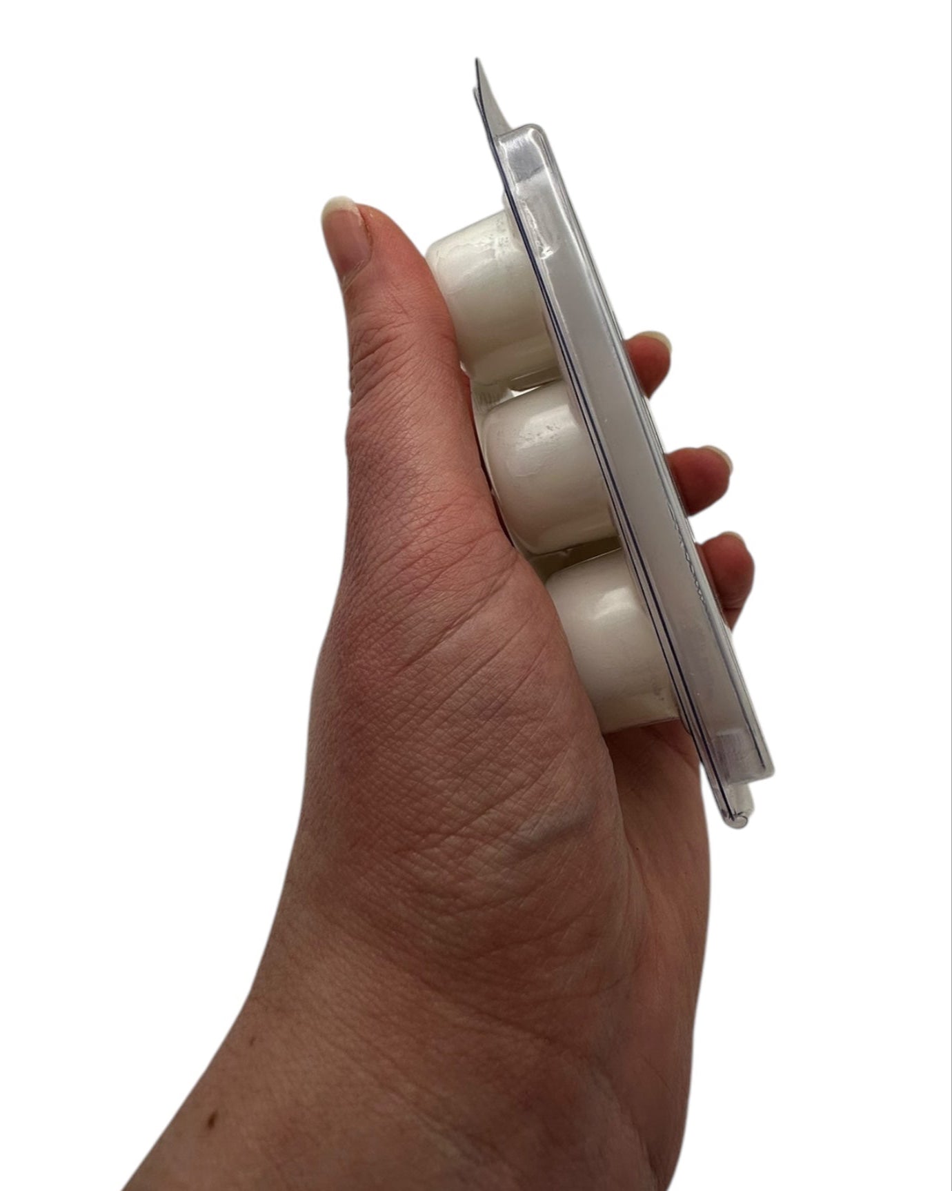 A hand holding a plastic clamshell white wax melts labeled "Marrakesh" on a white background.