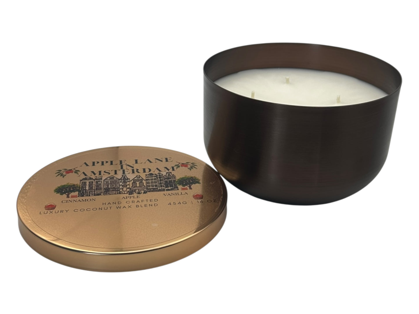 A bronze and gold candle tin labeled "Apple Lane in Amsterdam" with a decorative clear label with lid removed showing candle wicks and a smooth white candle top on a white background.