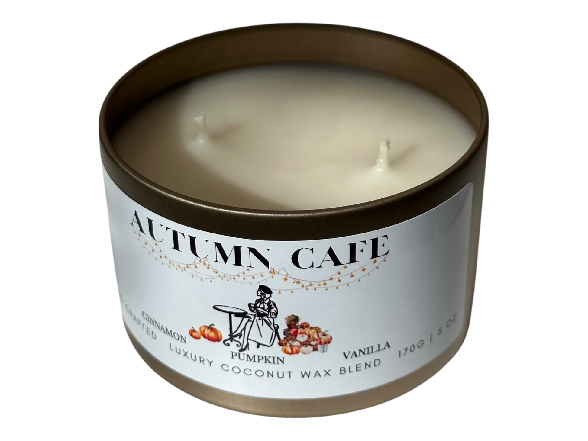 A gold candle tin with lid removed  labeled 'Autumn Cafe' on a white background.