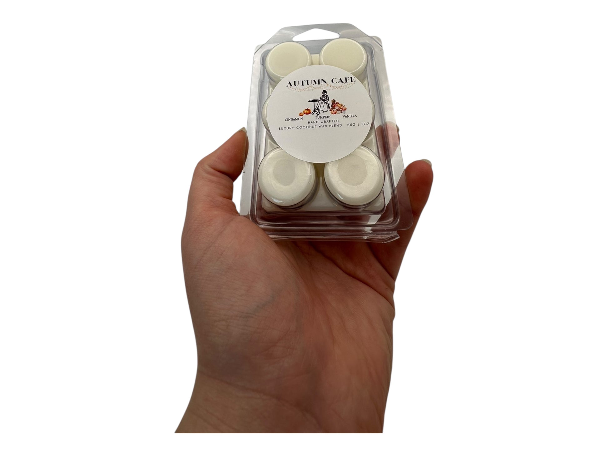Hand holding a package of white wax melts with 'Autumn Cake' label.