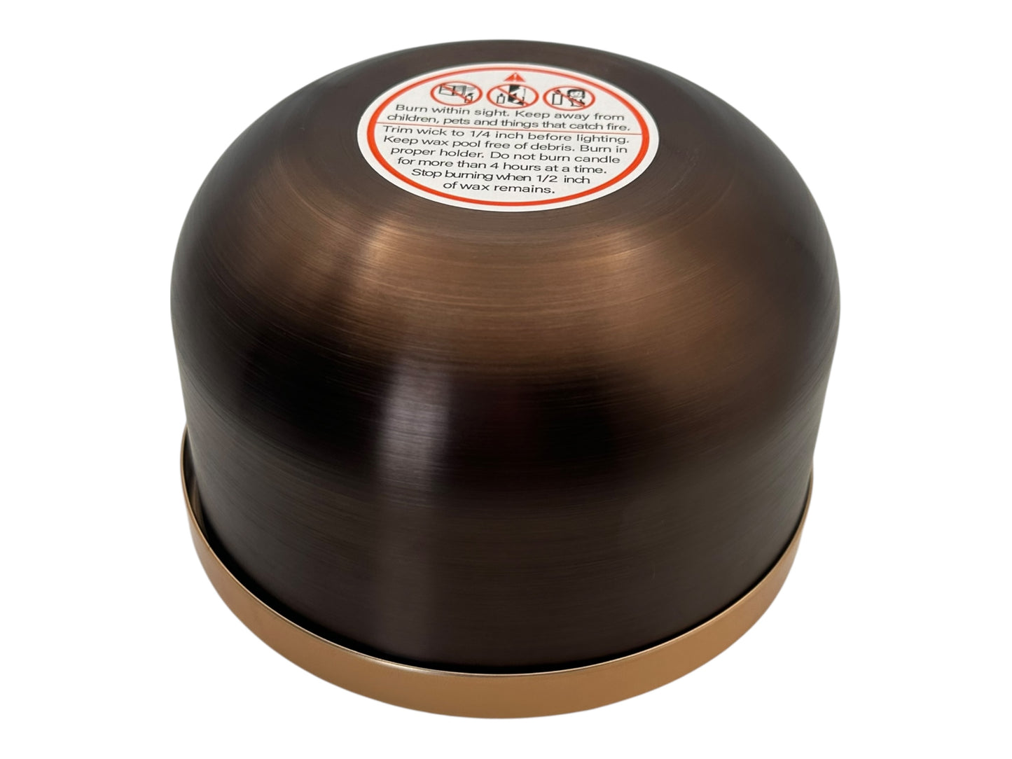 A bronze and gold candle tin flipped upside down showing a candle safety label on a white background.