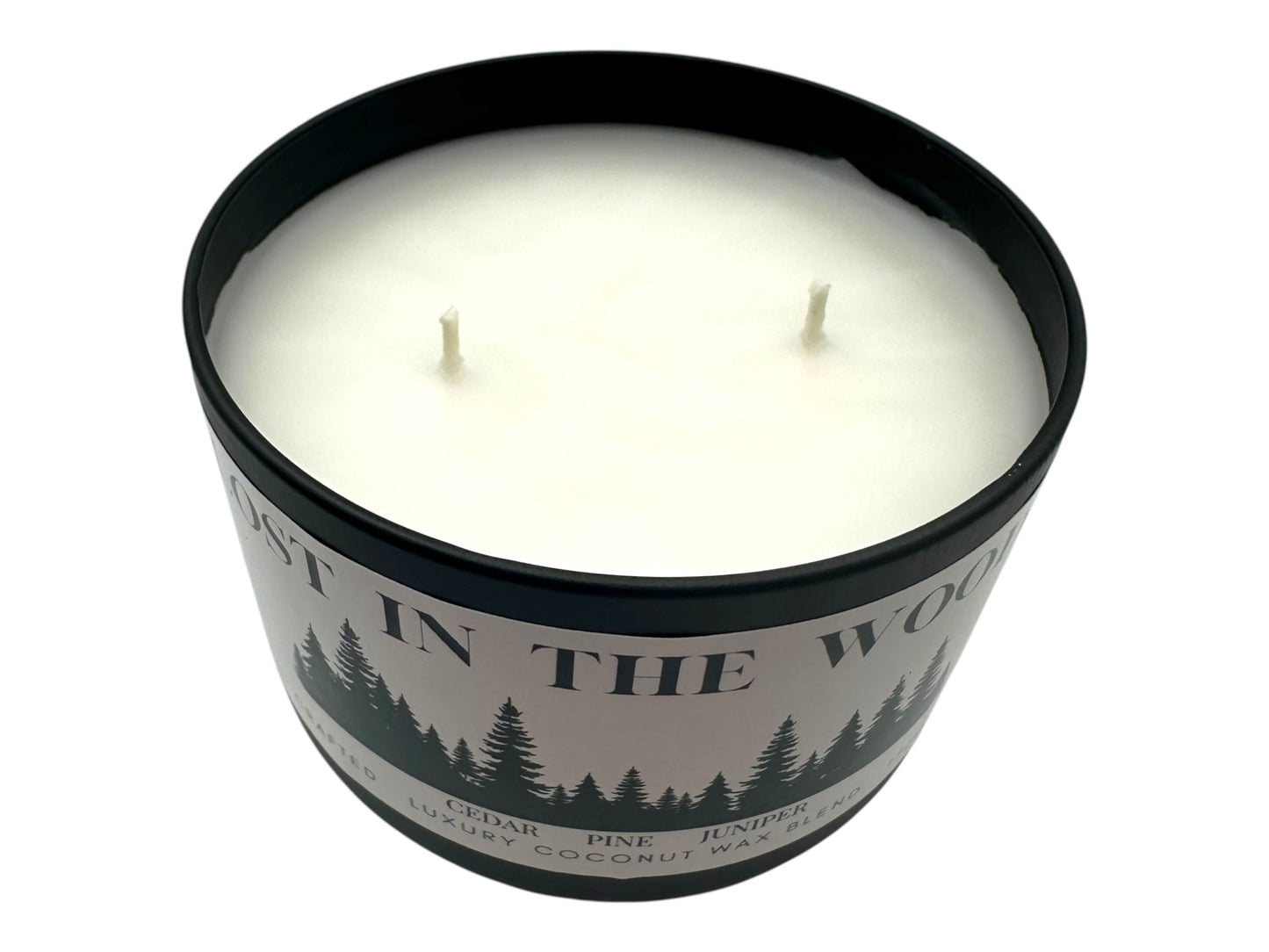 A black candle tin labeled "Lost in the Woods" with lid removed two wicks and as smooth candle top on a white background.
