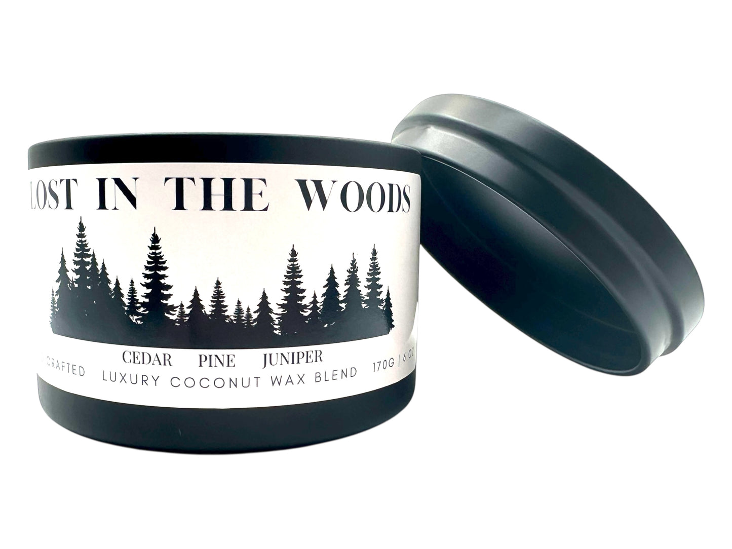 A  black candle tin labeled "Lost in the Woods" with lid removed on a white background.