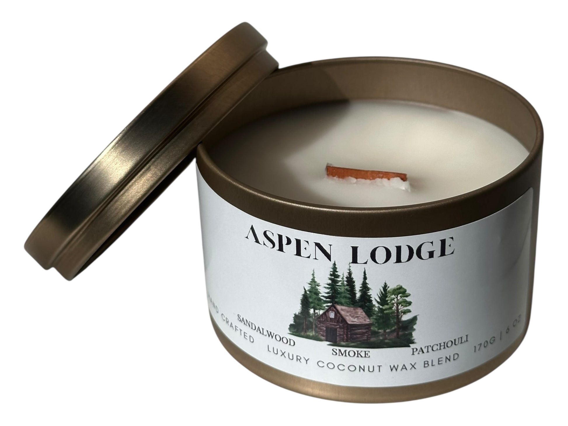 A gold candle tin with lid removed showing a wood wick and a smooth white candle top labeled 'Aspen Lodge' on a white background.