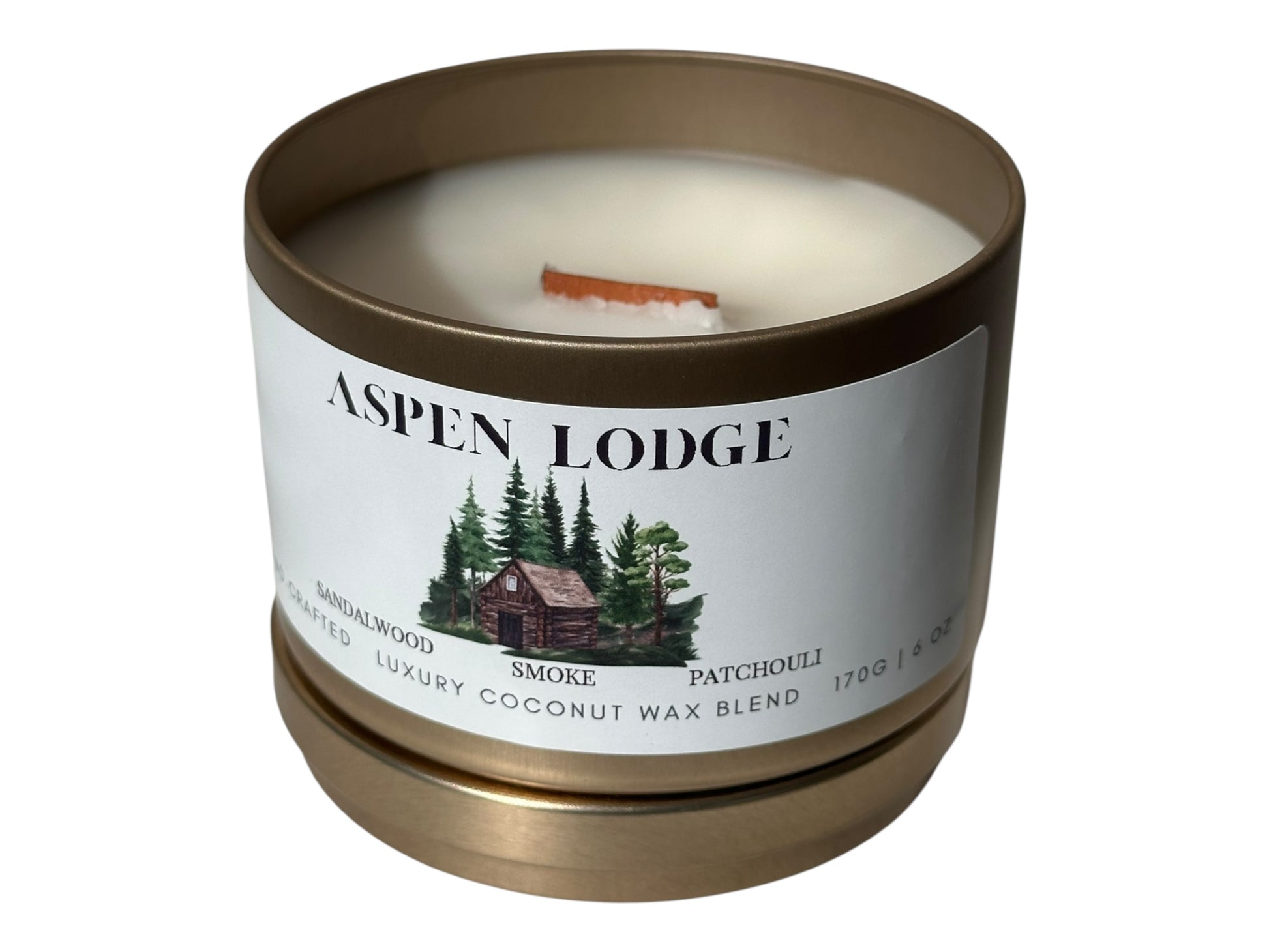 A gold candle tin with the lid removed a smooth white candle top and wood wick labeled 'Aspen Lodge' on a white background.