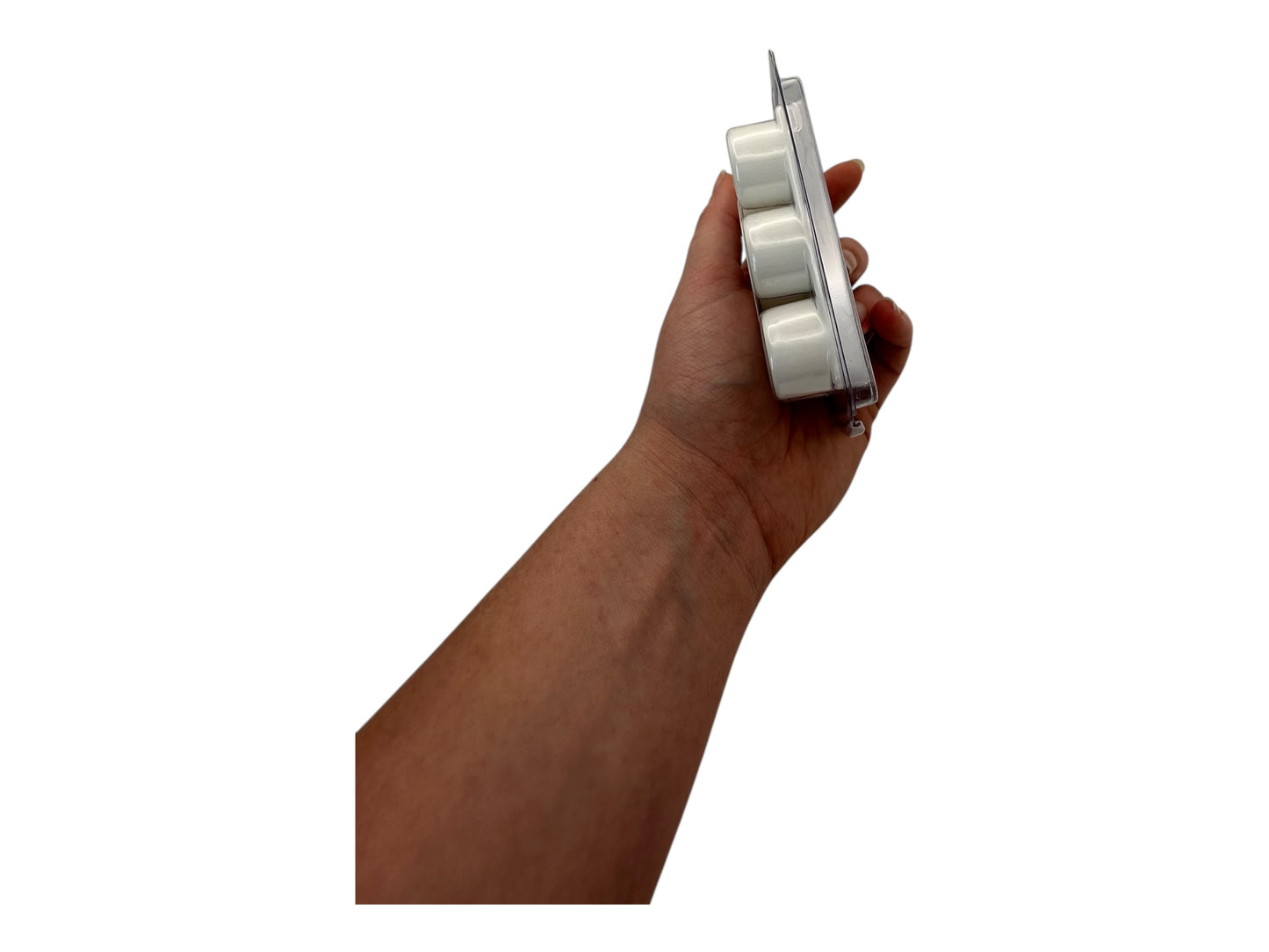 A hand holding white wax melts In full side view on a white background.