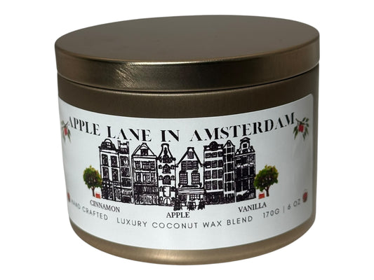 A gold candle tin with 'Apple Lane in Amsterdam' label on a white background.