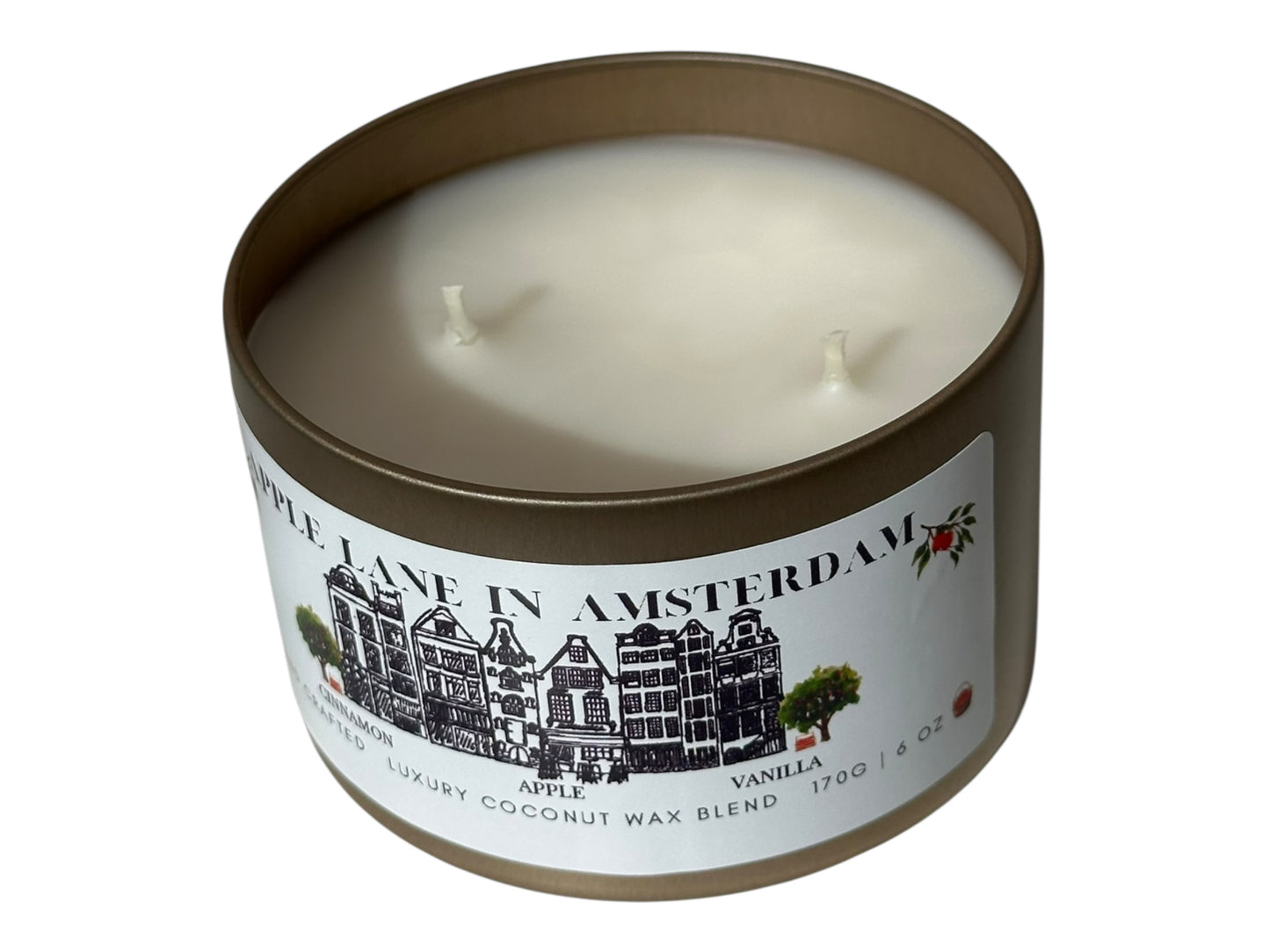 A gold candle tin with lid removed showing two cotton candle wicks and a smooth white candle top labeled "Apple Lane in Amsterdam" on a white background.