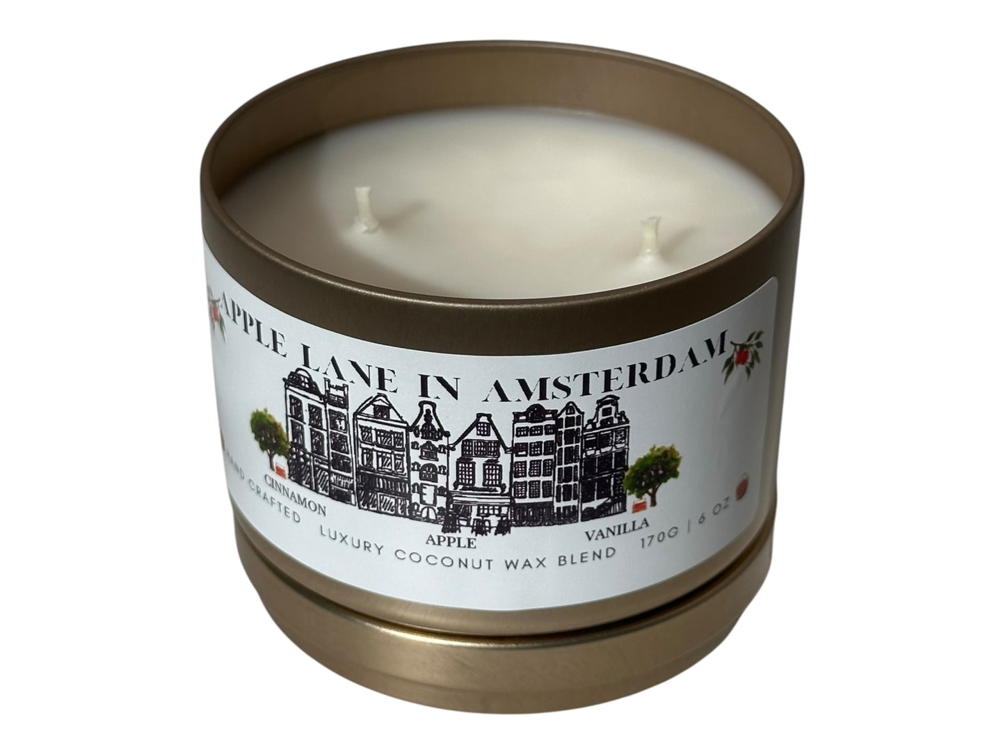A gold candle tin with lid removed labeled 'Apple Lane in Amsterdam' on a white background.