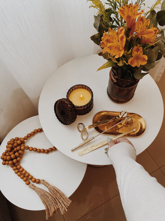 Candle wick trimmer, Snuffer, Wick Dipper, and metal Candle tray with candle resting o a table on a white background.