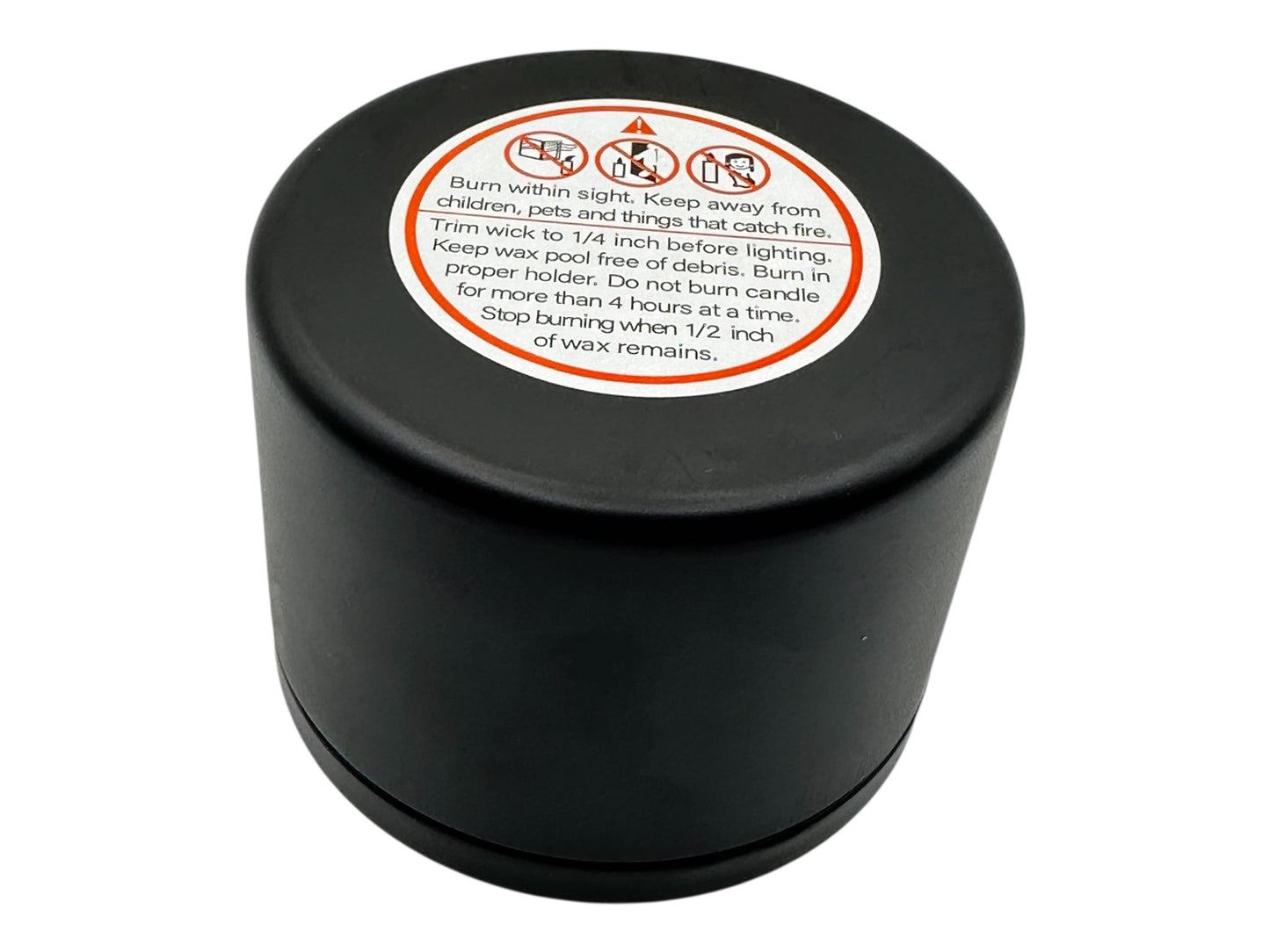 Black candle container with a warning label on a white background