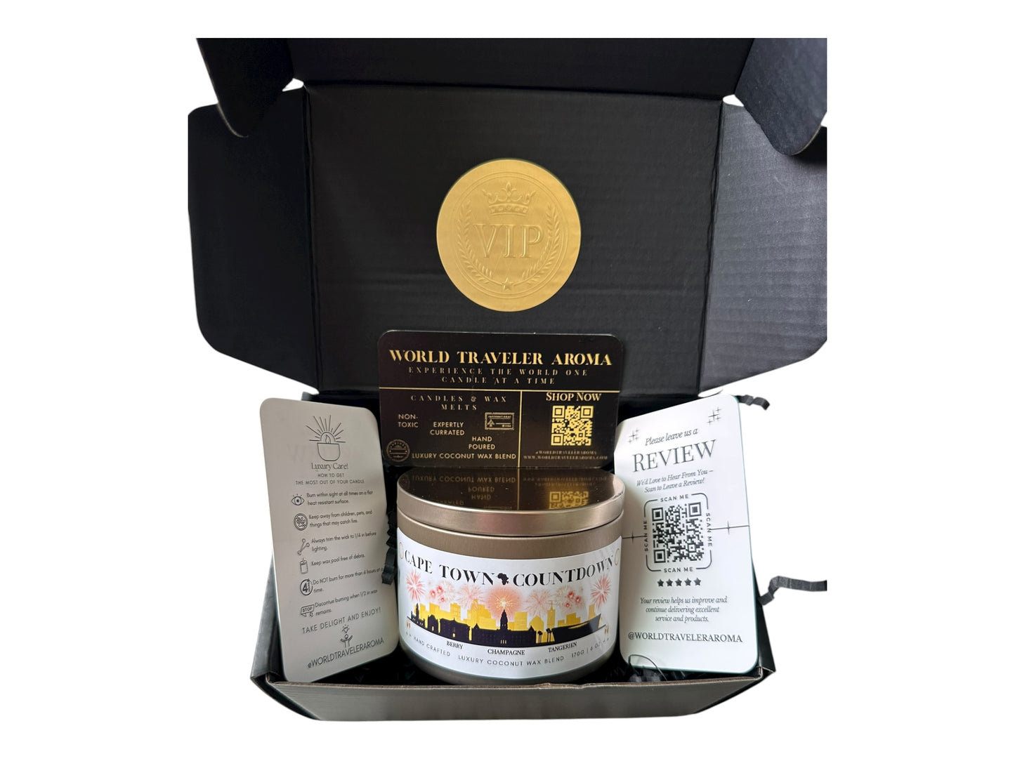  black gift box with a gold VIP sticker on the lid inside the box a gold candle tin labeled "Cape Town Countdown" a candle care card instructions, a please review us card, and a World Traveler Aroma business card.