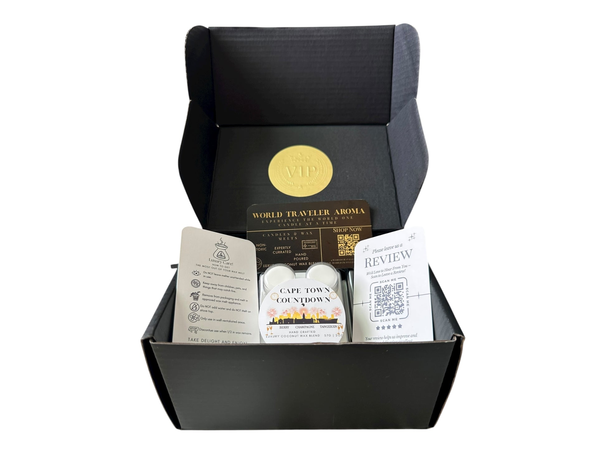 A black gift box with a gold VIP sticker on the lid inside the box a white coconut wax melt labeled "Cape Town Countdown" a wax melt care instructions card, a please review us card, and a World Traveler Aroma business Card on a white background.