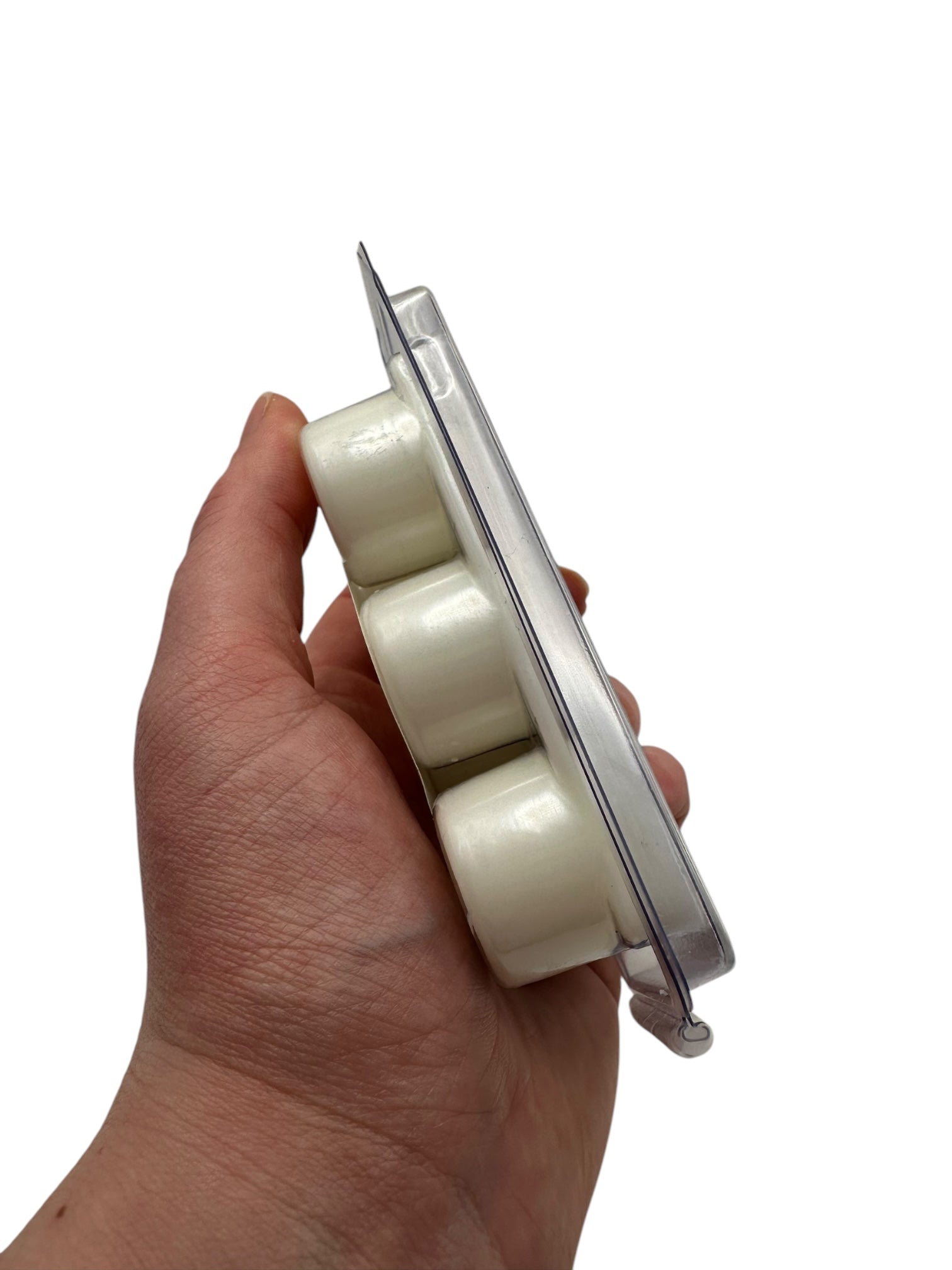Hand holding a white wax melt on a white background.