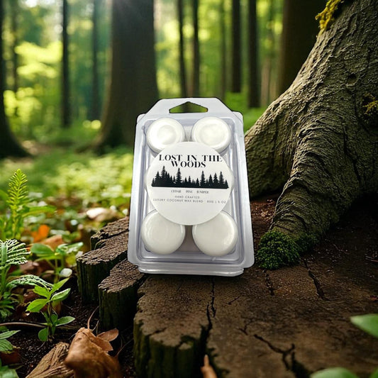 A white wax melt in clear clamshell labeled lost in the woods on a background of a forest.