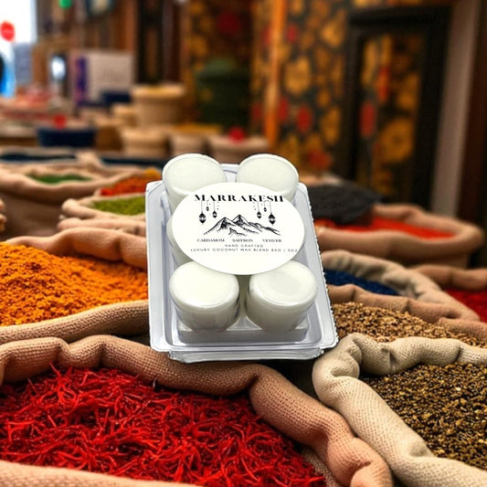 A white wax melt labeled Marrakesh resting on a pile of spice with a market in the background.