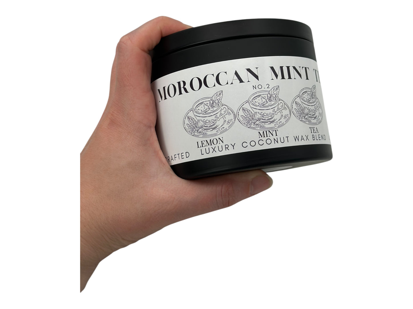 Hand holding a container of Moroccan Mint Tea candle tin with a white background