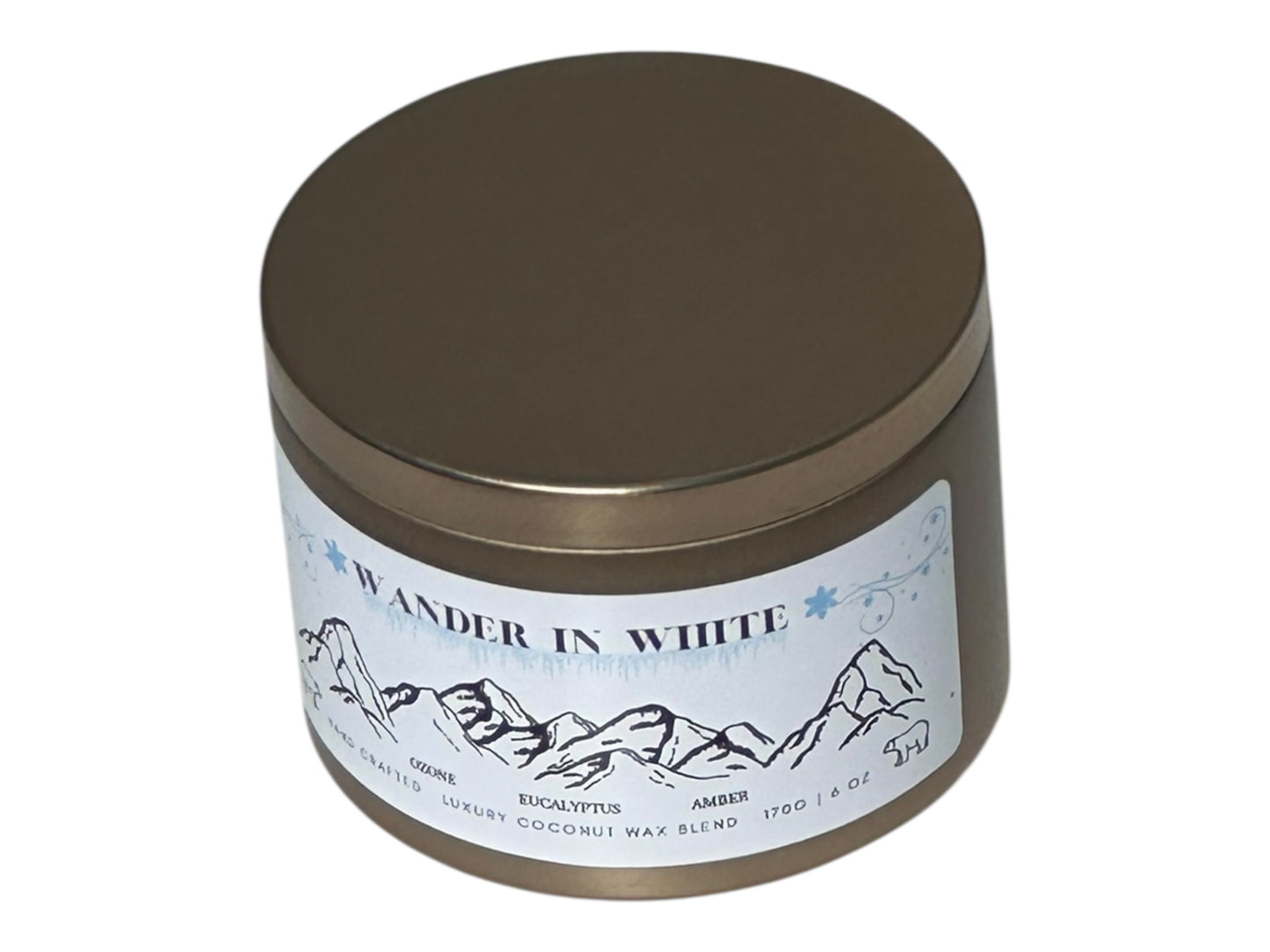 a gold Candle tin labeled 'Wander in White' with mountain design on a white background
