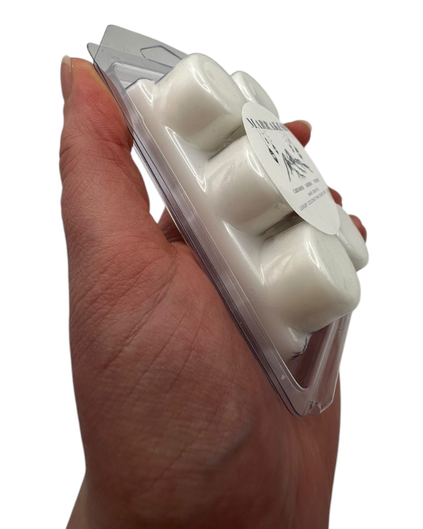 A hand holding white wax melts labeled 'Marrakesh' on a white background.