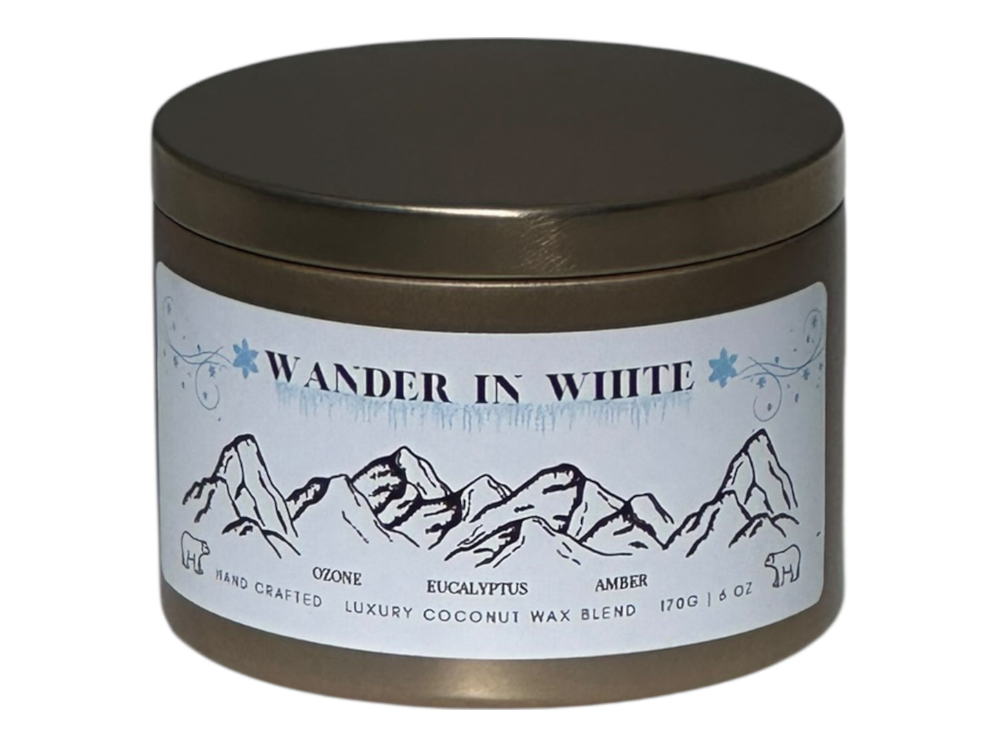 A gold candle tin with 'Wander in White' label featuring mountain design on a white background.