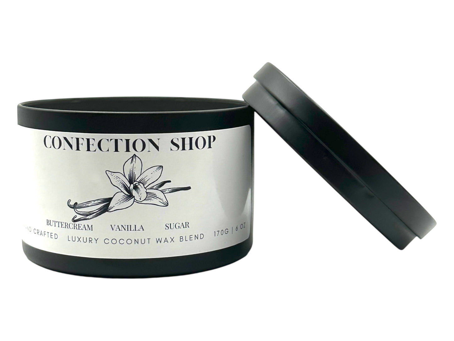 A black candle tin labeled "Confection Shop" lid removed and lying next to the candle on a white background. 