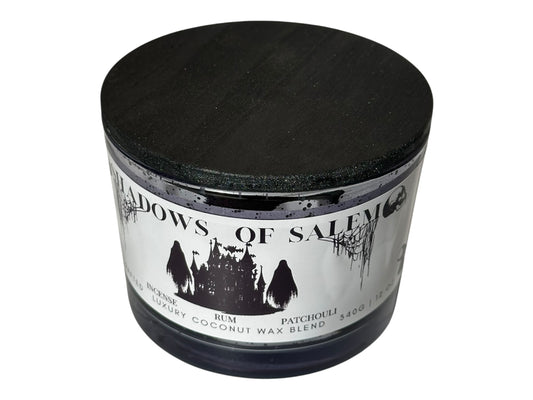 A purple candle jar with pearl black wooden lid  labeled 'Shadows of Salem' on a white background.