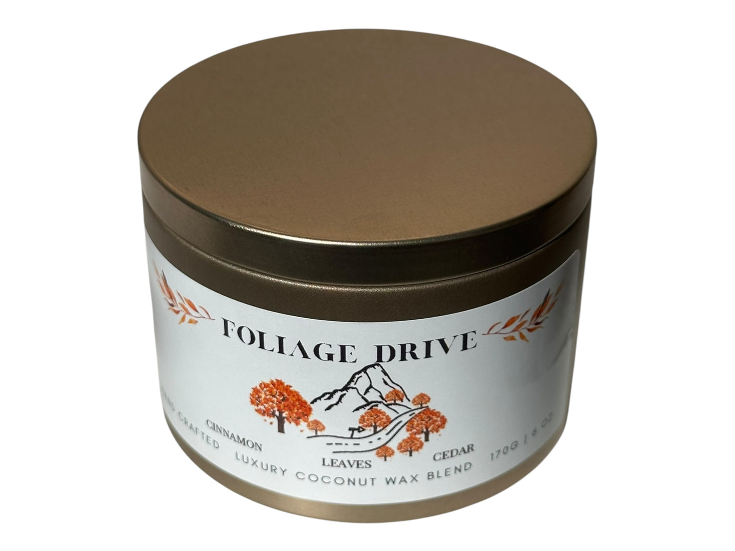 A gold candle tin with 'Foliage Drive' label on a white background.