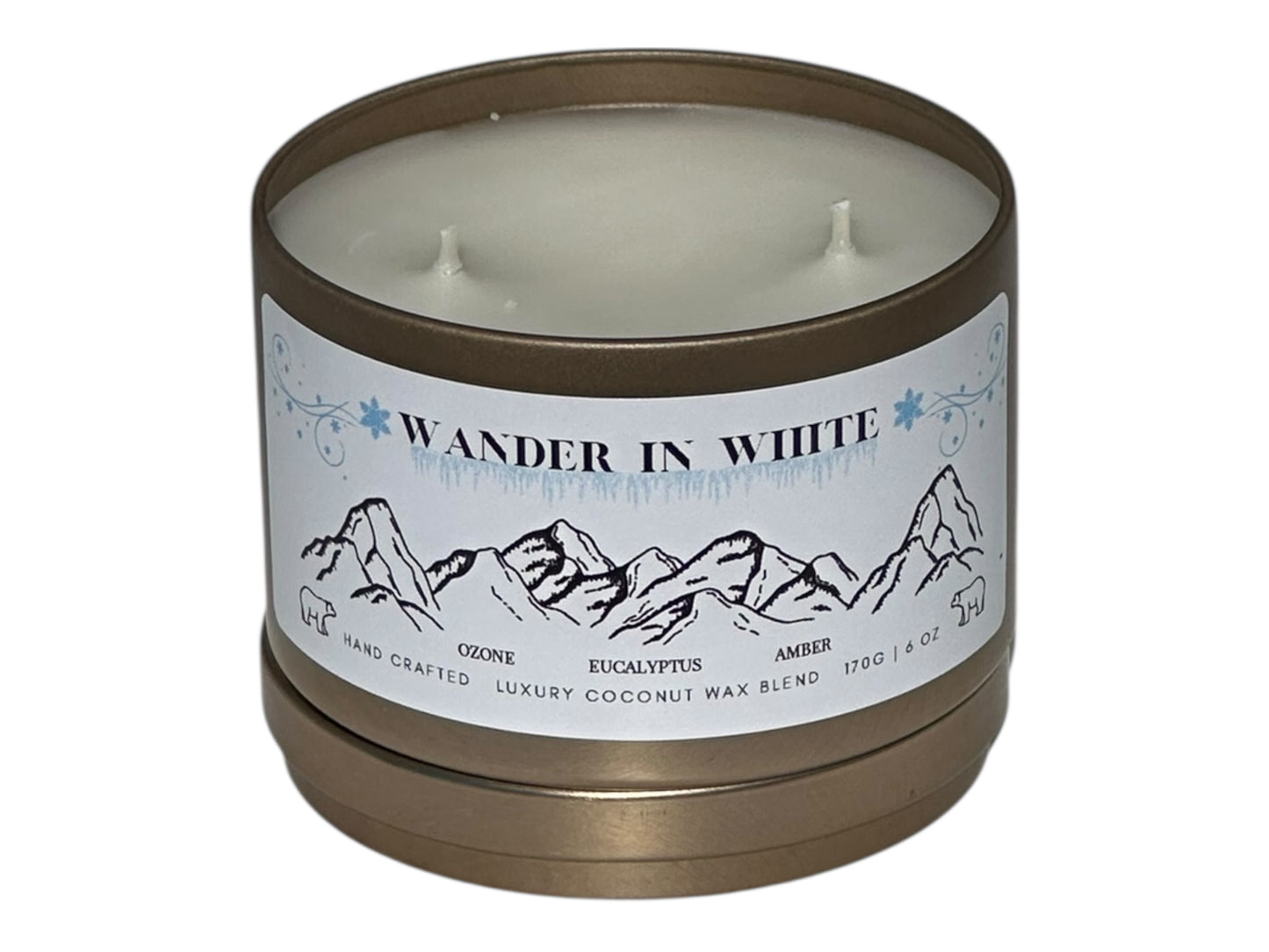 A gold candle tin labeled "Wander in White" with lid removed on a white background.