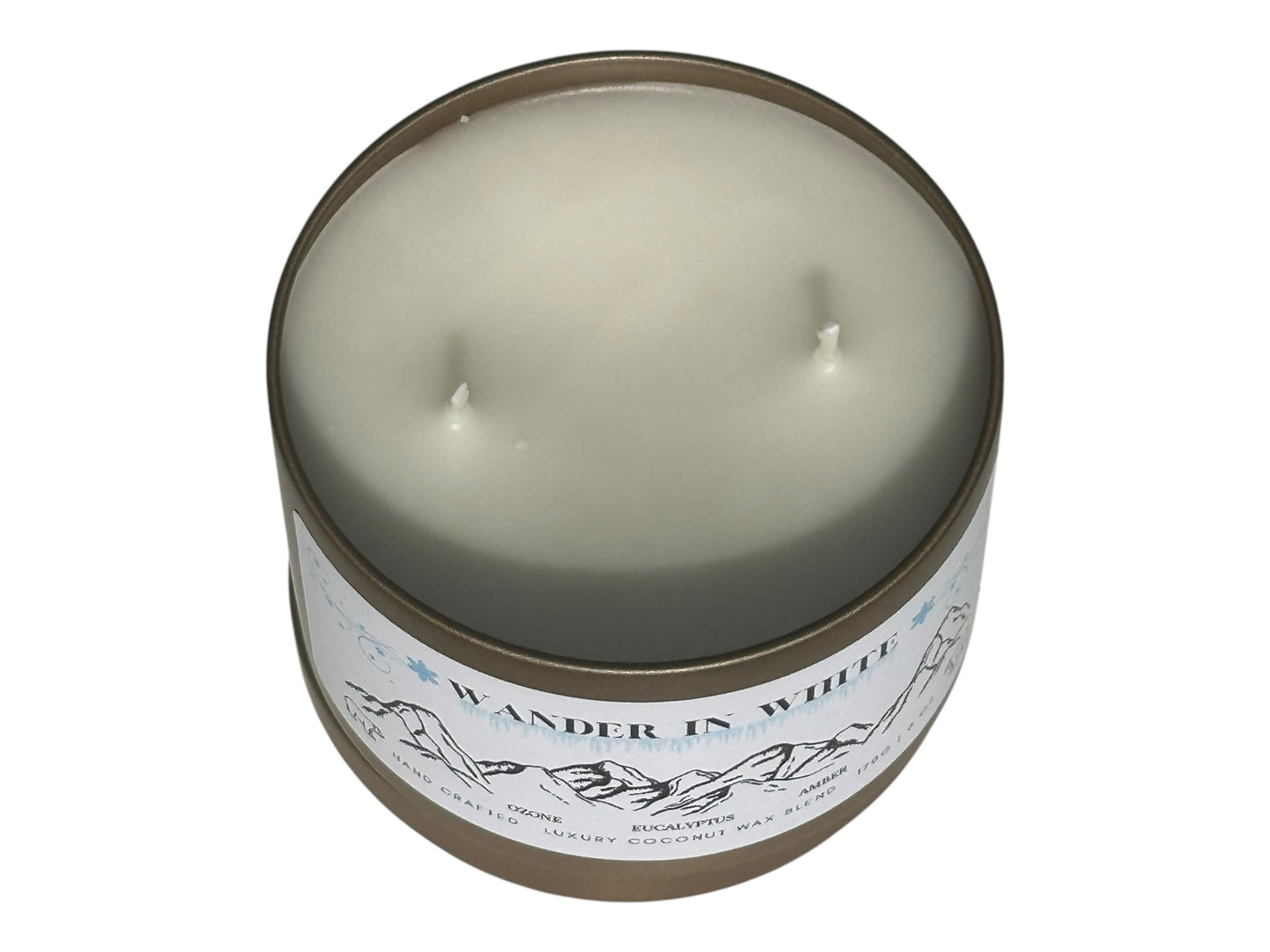 A gold candle tin labeled "Wander in White" with lid removed displaying two candle wicks on top on a white background.