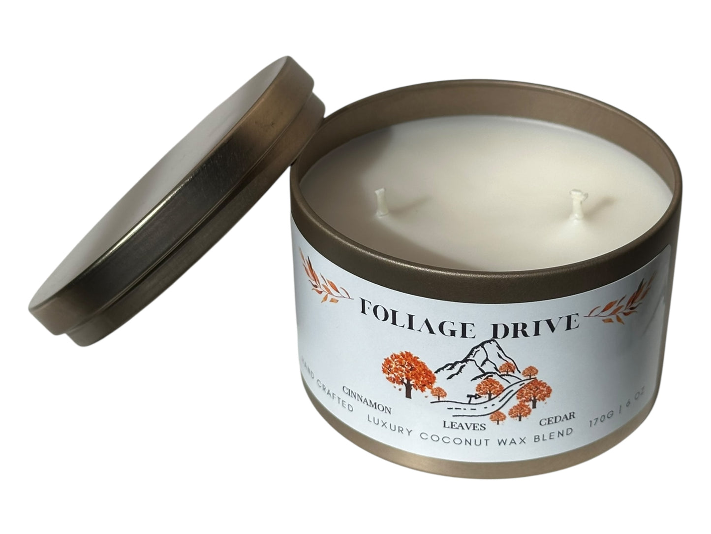 A gold candle tin with lid removed labeled 'Foliage Drive' on a white background.
