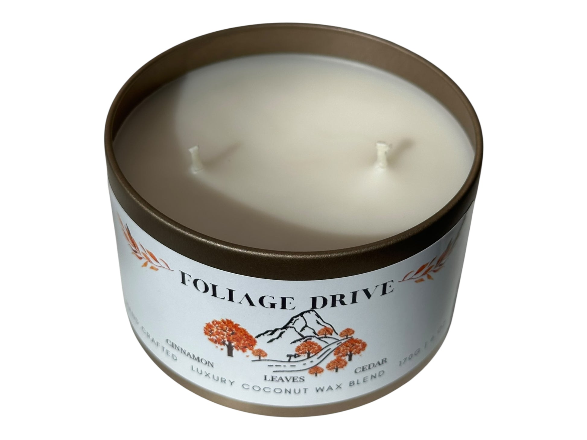 A gold candle tin with lid removed labeled 'Foliage Drive' on a white background.