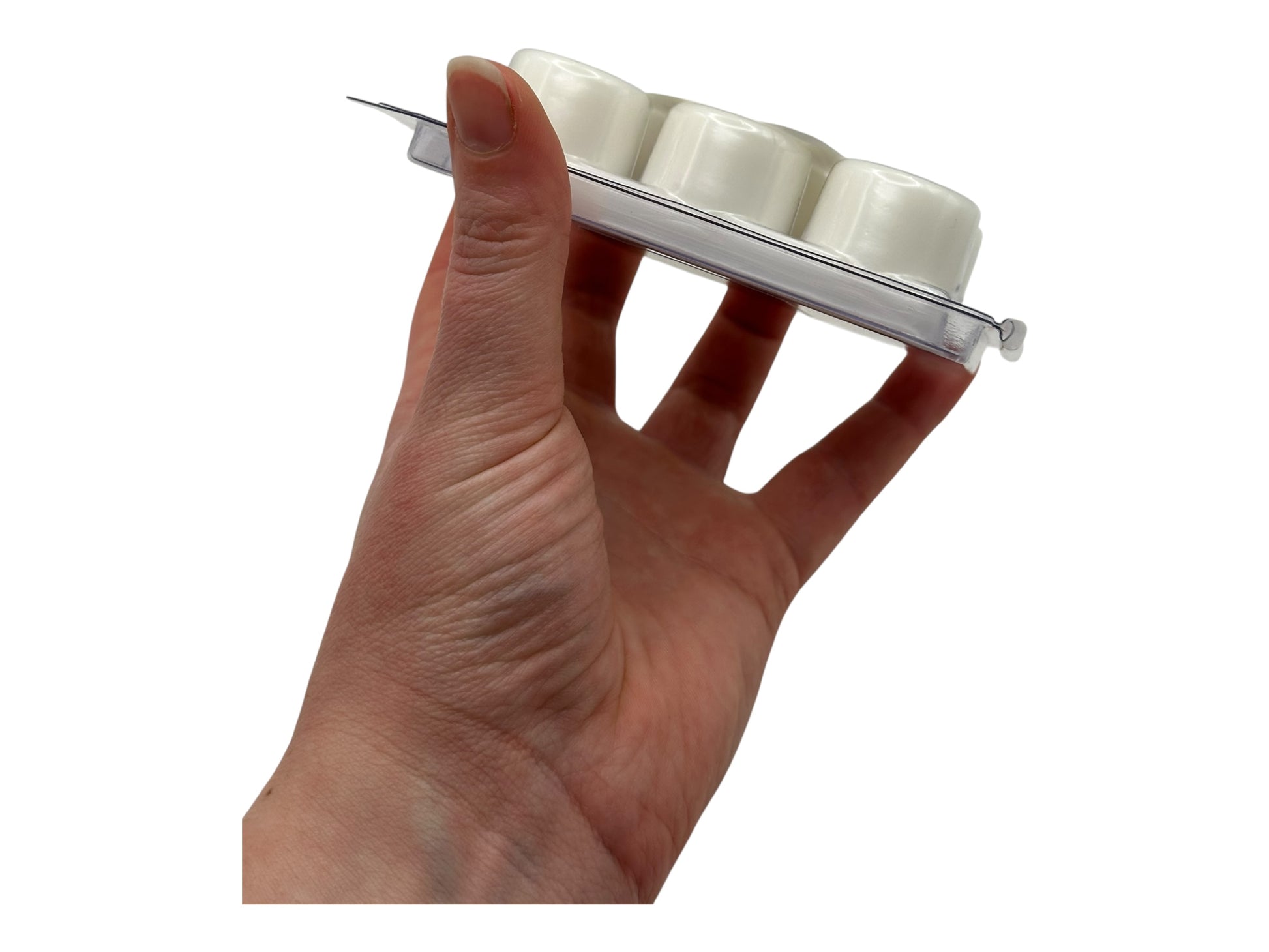 A hand holding white wax melts in a plastic clamshell on white background.