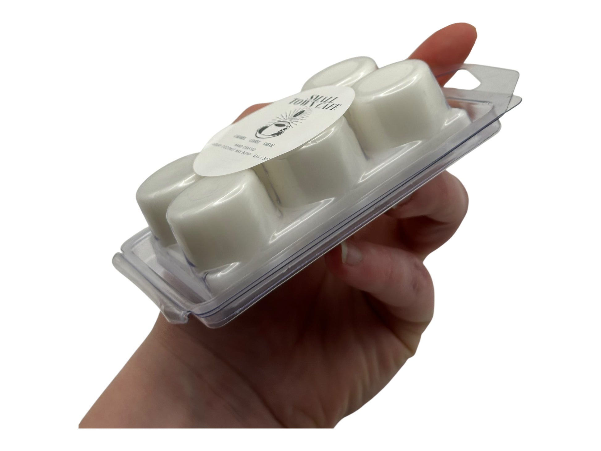A hand holdingA package of wax melts  labeled 'Small Town Cafe' on a white background.