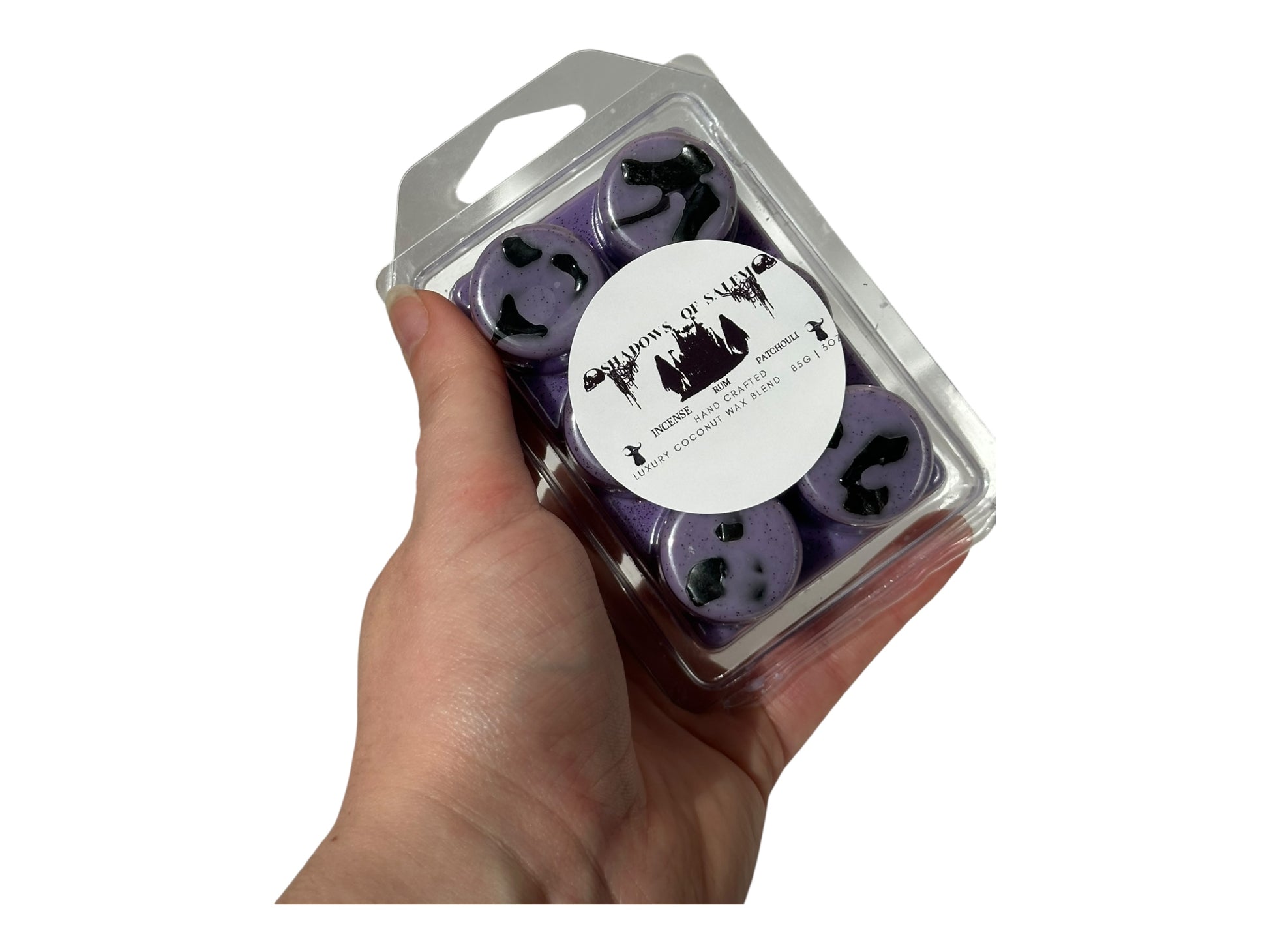 A hand holding purple wax melts labeled "Shadows of Salem" on a white background. 