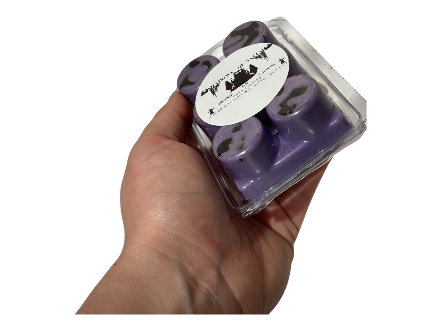 A hand holding purple wax melts labeled "Shadows of Salem" on a white background.