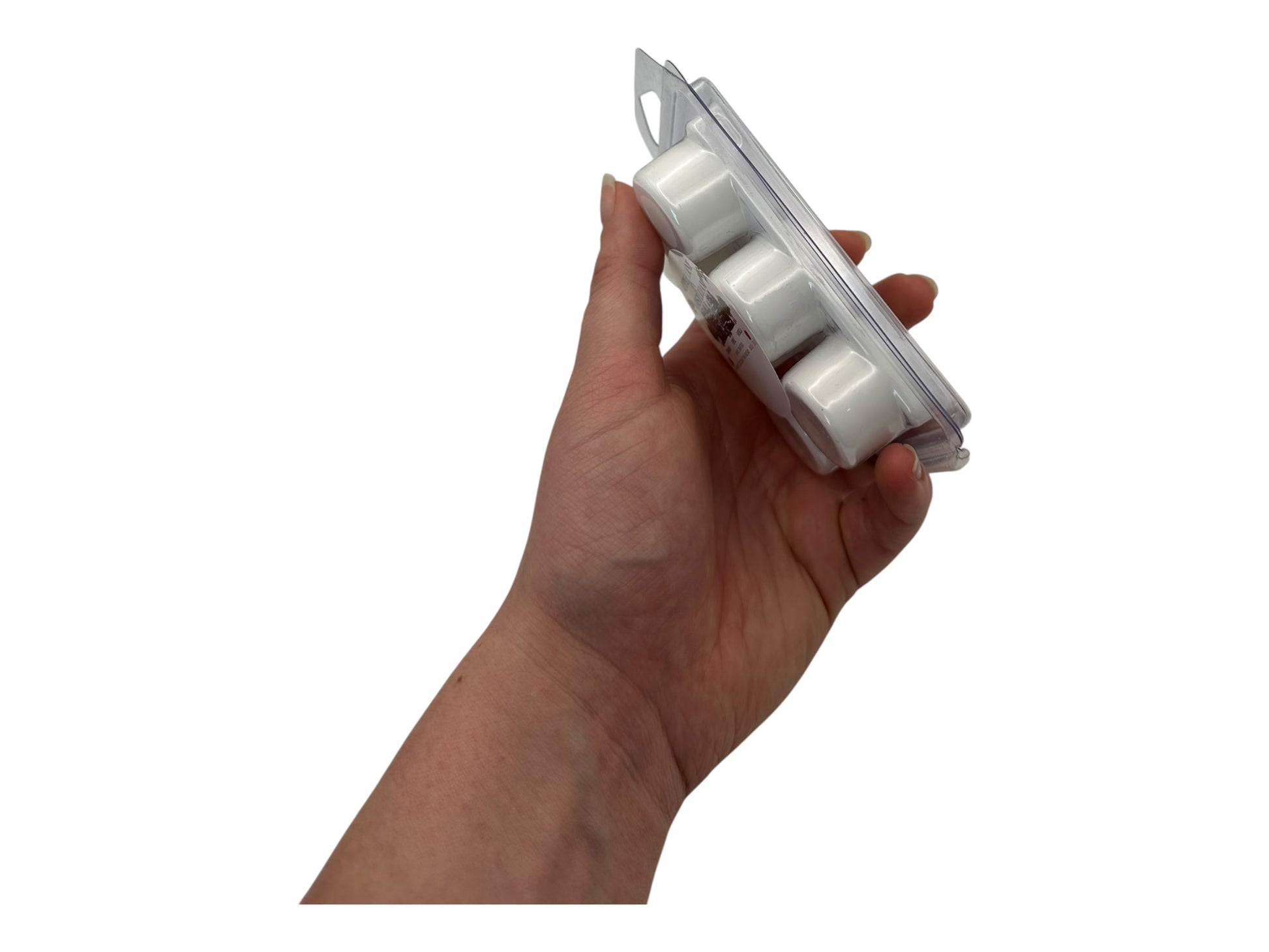 A hand holding white wax melts in a plastic clamshell in full side view on a white background.