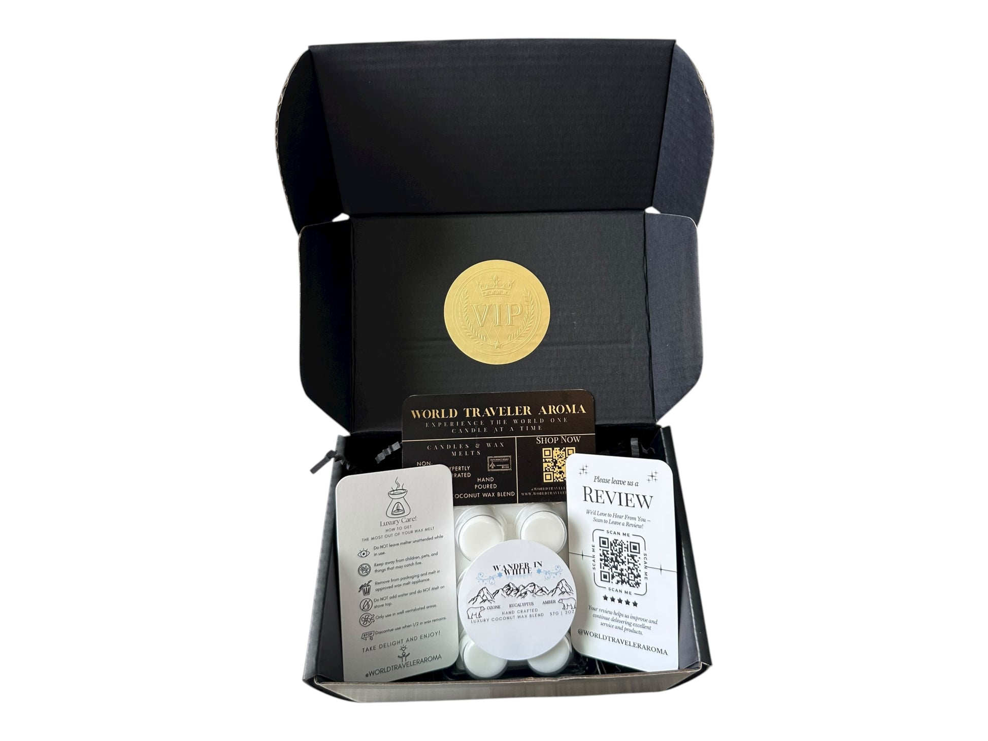 A black gift box with a gold VIP sticker on the lid with holiday wax melt labeled "Wander in White" a how to care card, please review card, and World Traveler Aroma Business Card on a white background.