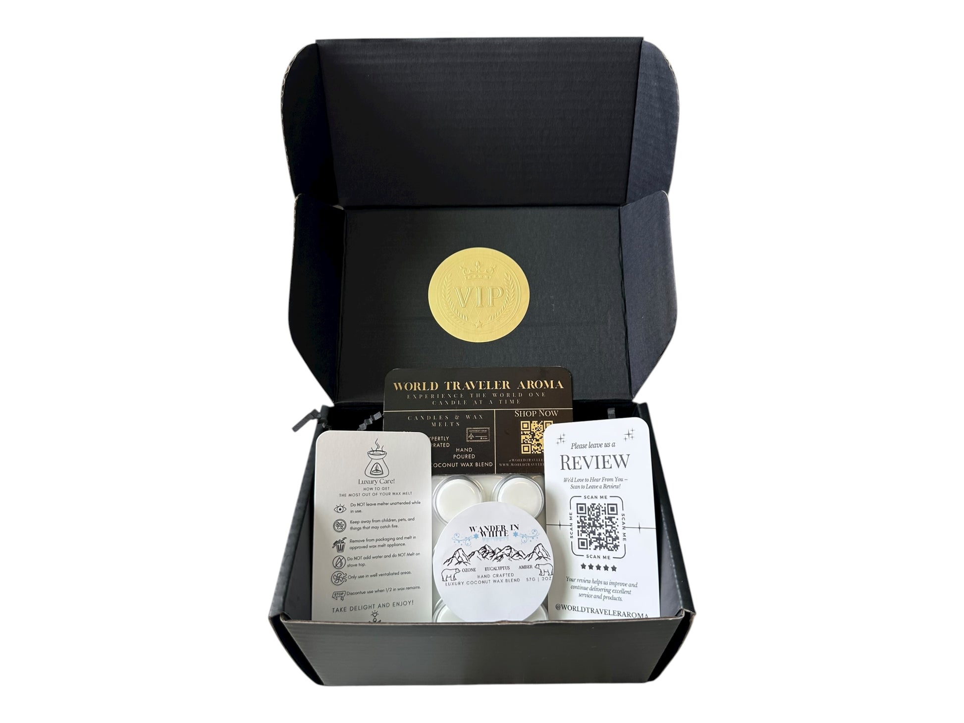 A black gift box with a gold VIP sticker on the lid with holiday wax melt labeled "Wander in White" a how to care card, please review card, and World Traveler Aroma Business Card on a white background.