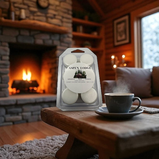 Package  of Aspen Lodge wax melts on a table with a cup of coffee in front of a fireplace.