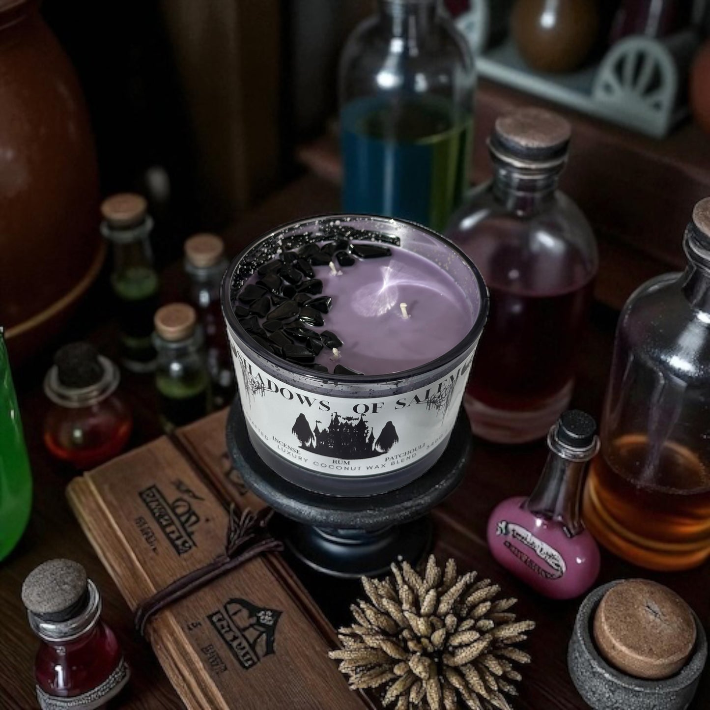 A purple candle labeled 'Shadows of Salem' surrounded by various bottles and decorative items on a wooden surface.