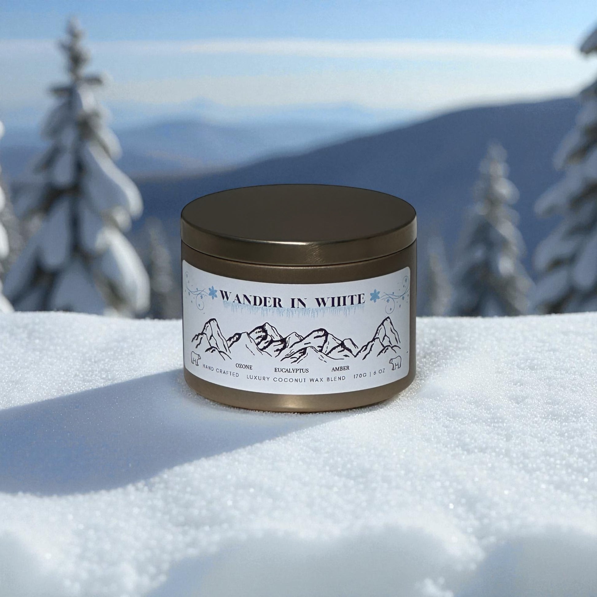 Gold Candle in a tin labeled 'Wander in White' on a snowy landscape with trees and mountains.