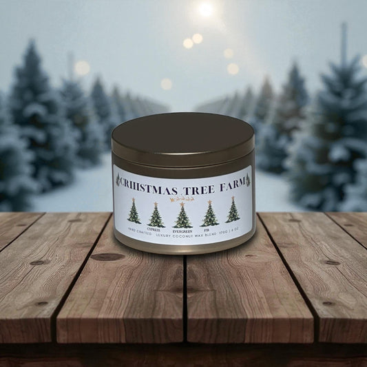 Gold candle tin sitting on a wood deck with snow covered Christmas trees in the background.