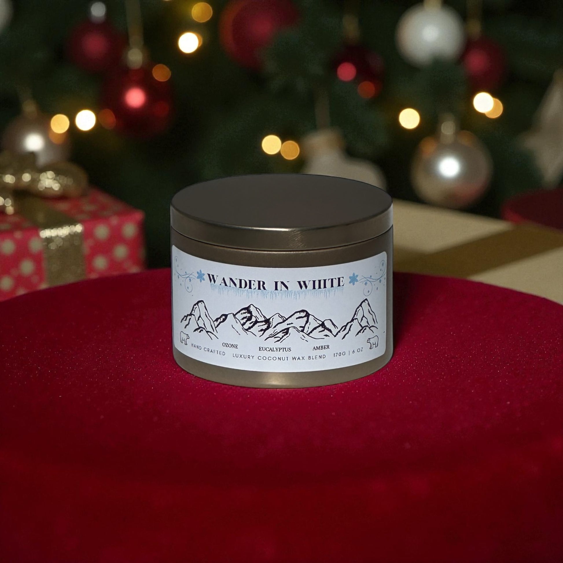 A gold candle tin lambed "Wander in White" on a red rug with Christmas presents and a decorated  Christmas Tree in the background. 