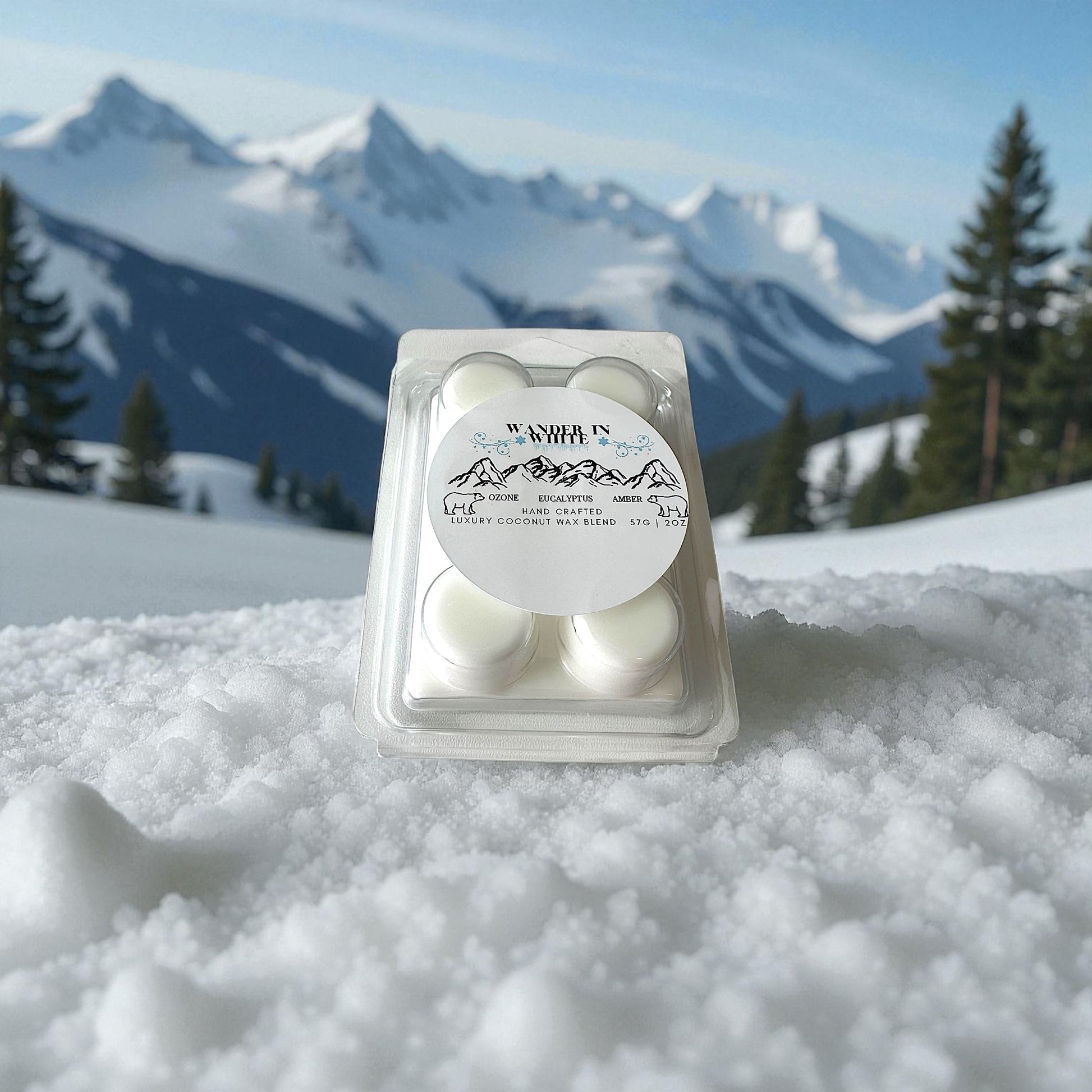 A holiday wax melt labeled "Wander in White" sitting on fresh snow with a snow covered mountains and pines in the background.