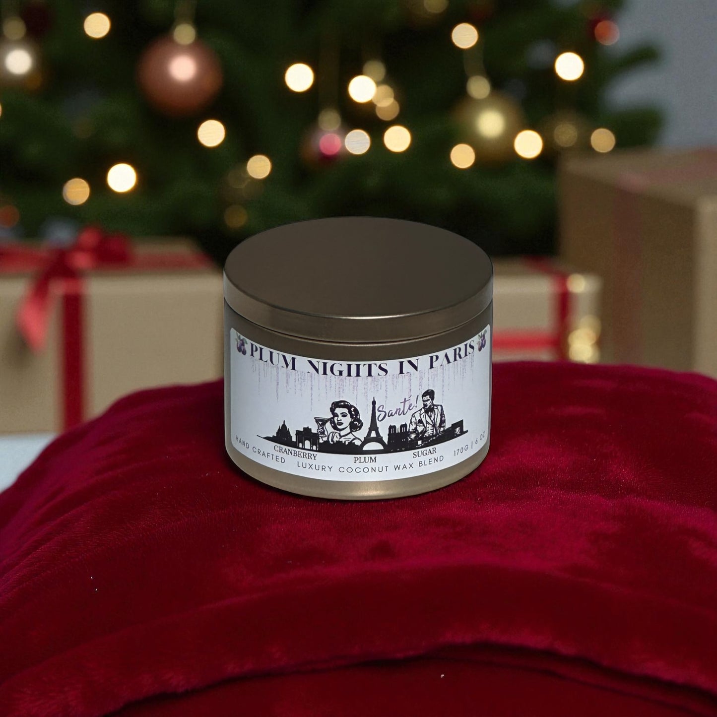 A gold candle tin labeled "Plum Nights in Paris" sitting on a red blanket with Christmas presents and Christmas tree in the background.