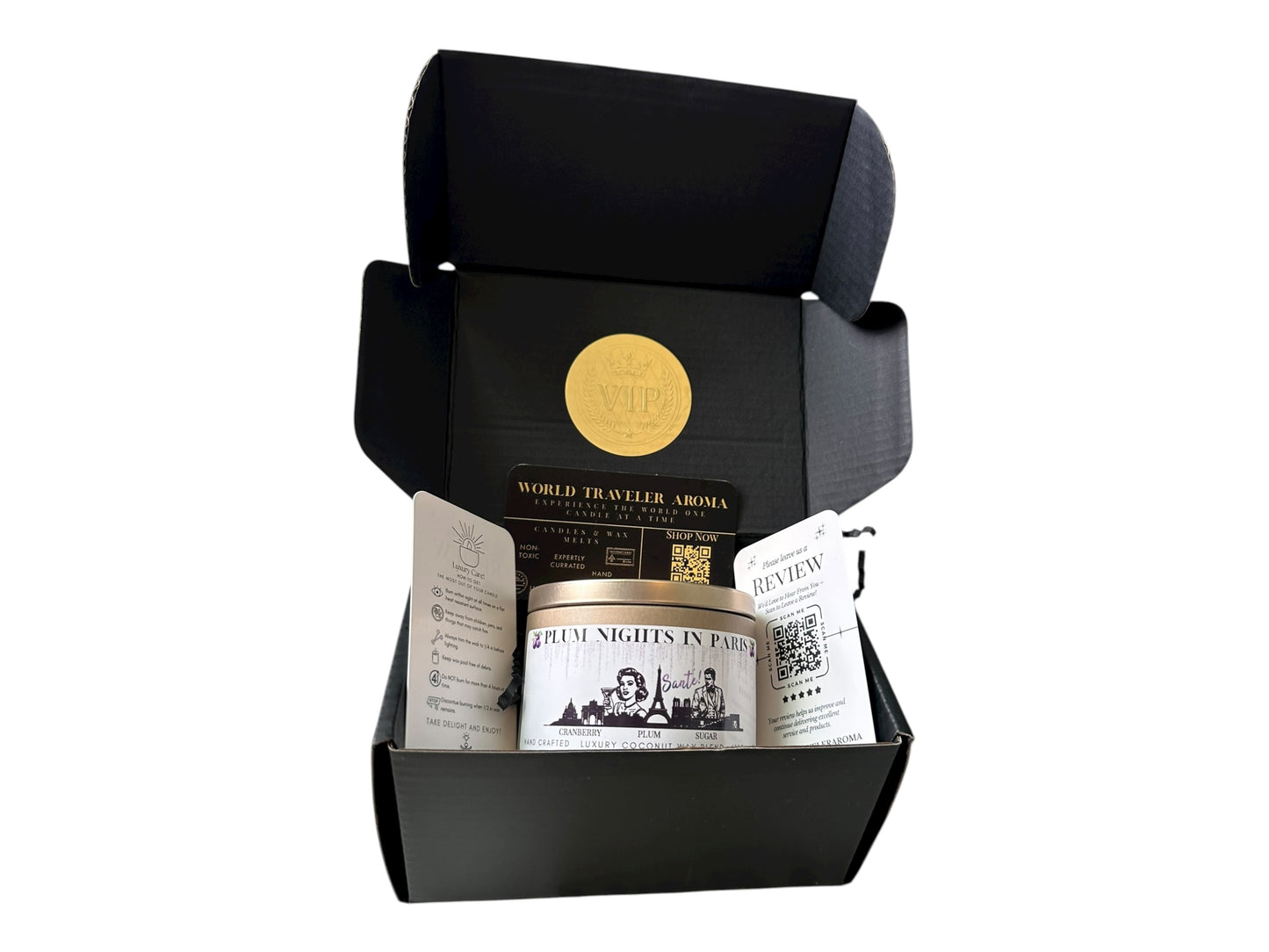 A black gift box with gold VIP sticker on the lid inside the box a gold candle tin labeled "Plum Nights in Paris" a candle care card instructions, a please review us card, and World Traveler Aroma business card on a white background.