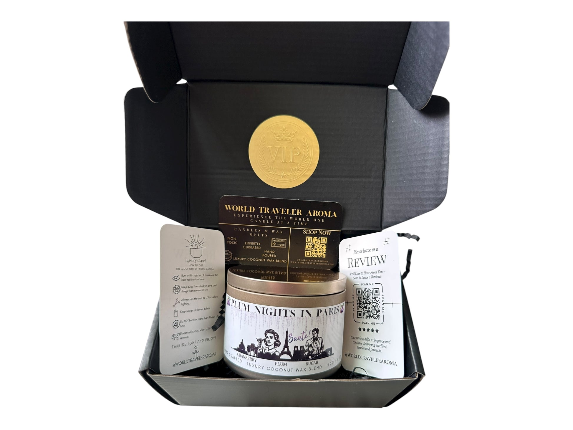 A black gift box with gold VIP sticker on the lid inside the box a gold candle tin labeled "Plum Nights in Paris" a candle care card instructions, a please review us card, and World Traveler Aroma business card on a white background.