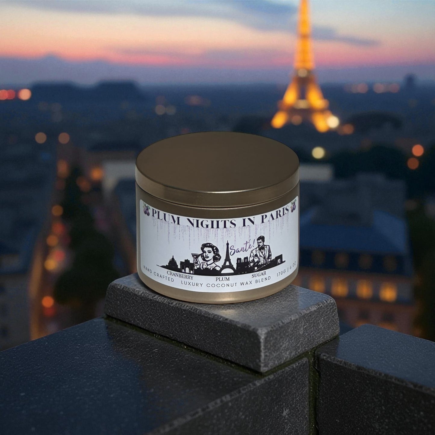 A gold candle tin labeled "Plum Nights in Paris" on a balcony over looking Paris and the Eiffel Tower at dusk.