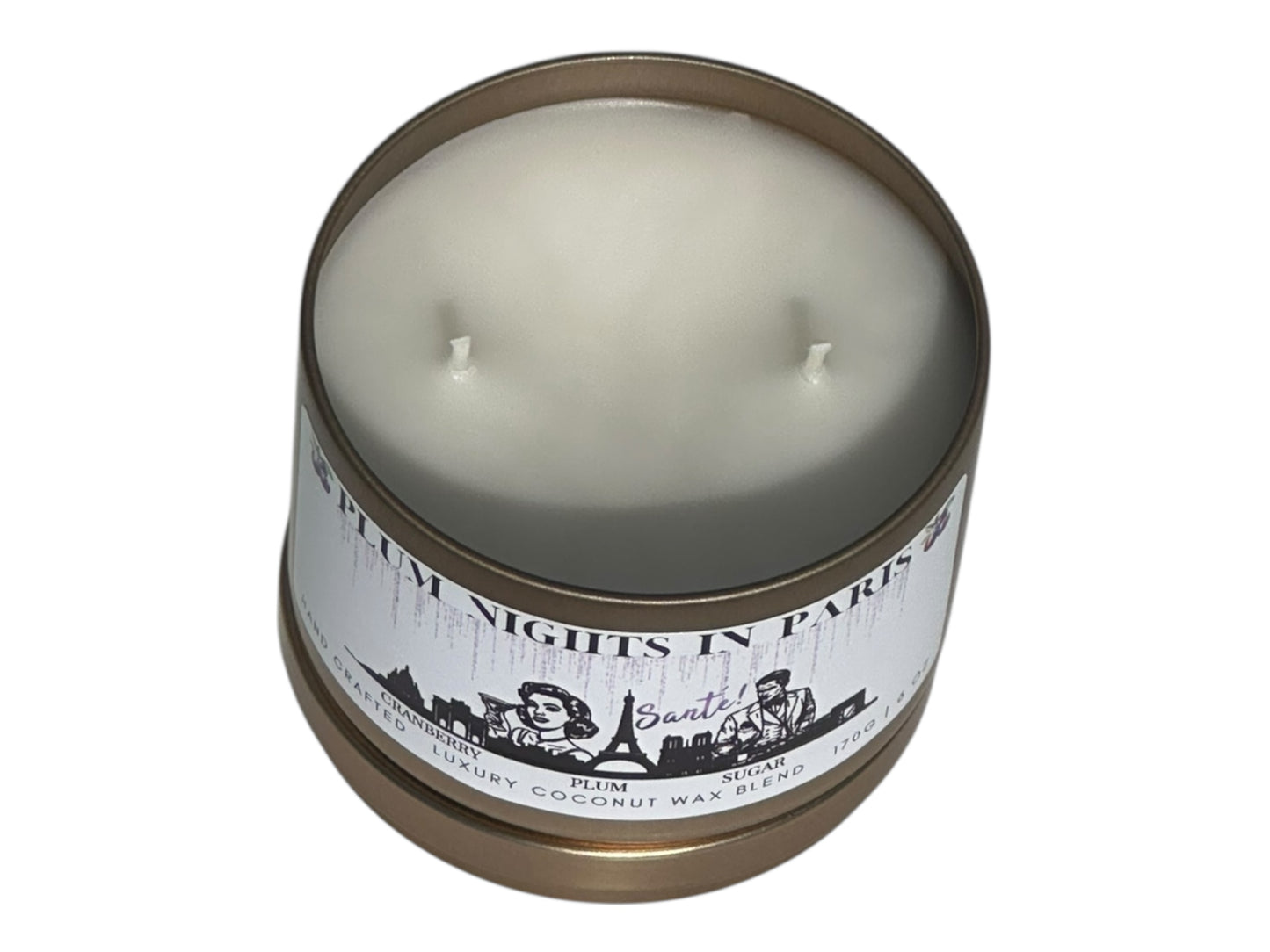 A gold candle tin labeled, "Plum Nights in Paris" on a white background with lid removed top view.