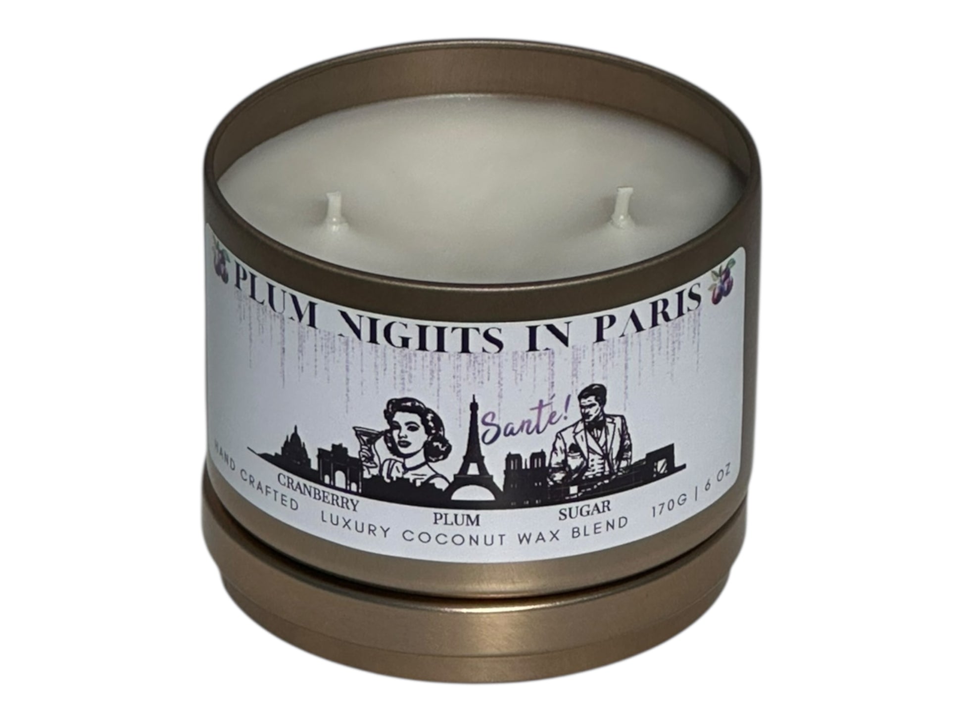 A gold candle tin labeled, "Plum Nights in Paris" on a white background with lid removed showing two candle wicks.